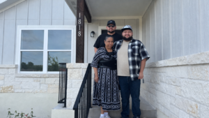 three family members standing on front porch smiling