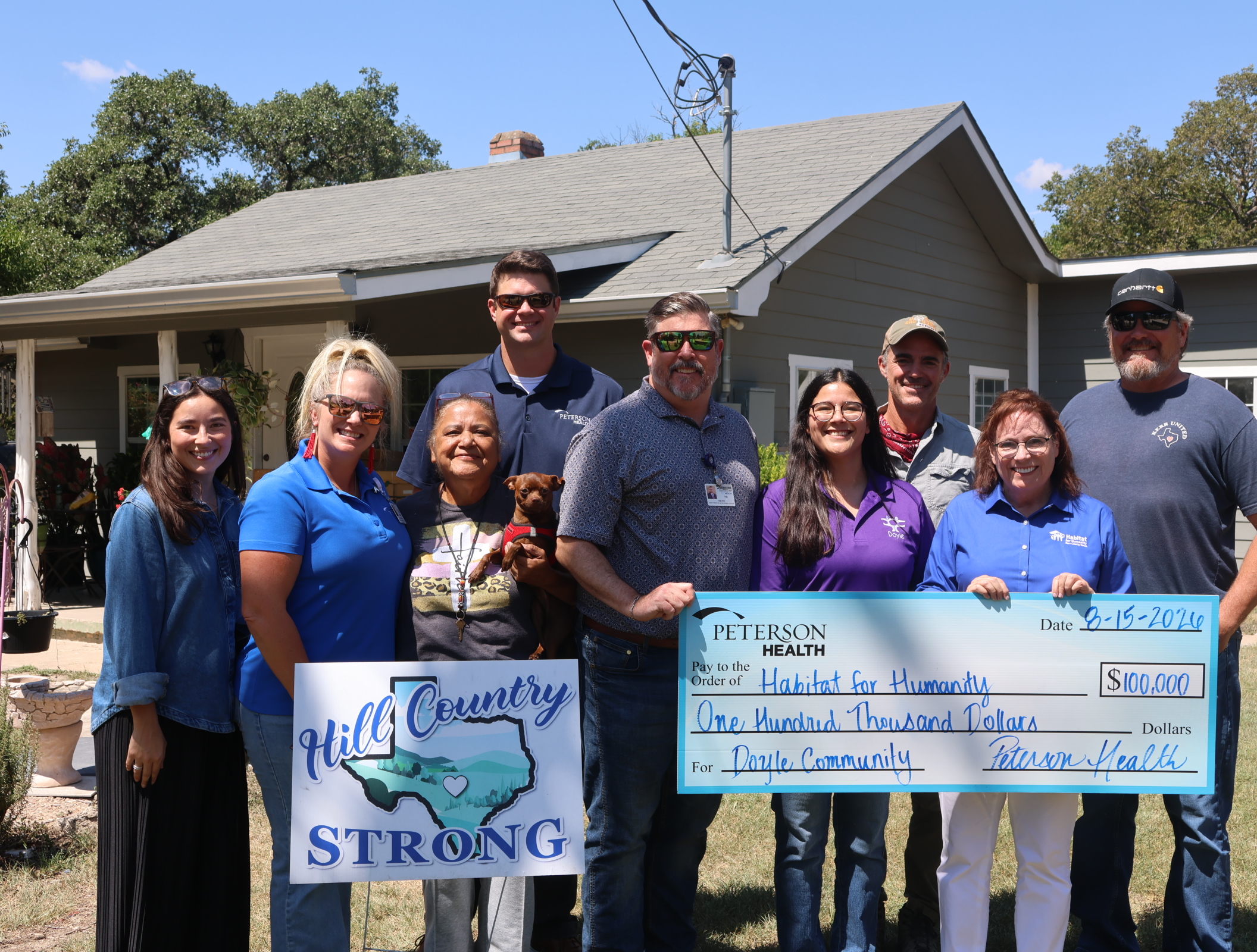 9 people standing in a group holding a very large check.